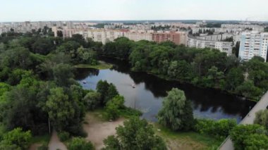 Kuzey Avrupa 'daki yeşil bir şehrin panoramik insansız hava aracı görüntüsü. Kumlu sahilleri olan bir adada insansız hava aracı vuruldu. Ukrayna 'daki Psel nehri üzerindeki yaya köprüsü, Sumy şehri. İnsanlar sahilde dinleniyor.