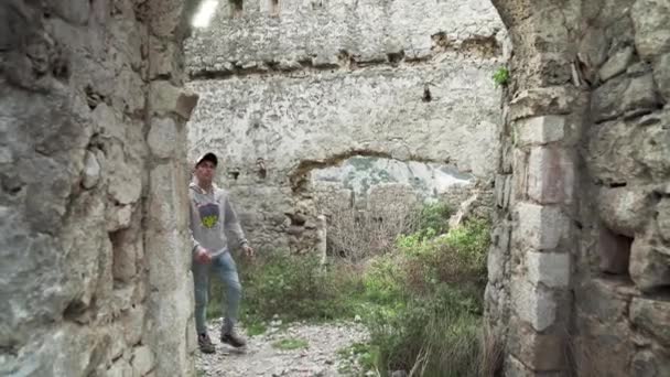 一个年轻人走在被毁的海海城堡里 那家伙在看黑山的风景 Sutomore Montenegro的要塞 在黑山的山上休息 在山上远足 — 图库视频影像
