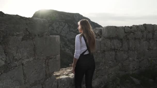 在黑山苏托莫尔市的Haj Nehai要塞 一个女孩在破烂不堪的城堡里走着 这个女孩在山中的背景下摆姿势 在山上远足 中世纪的要塞 — 图库视频影像