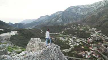 Harap olmuş Hac Nehai kalesinin kıyısında bir vadi ve dağların arkasında duran genç bir adam. Adam Karadağ 'ın dağlarının arka planında poz veriyor. Sutomore 'daki Kale