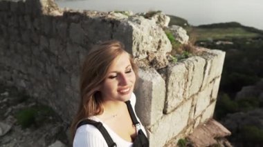 Harap olmuş Hac Nehai Kalesi 'nde bir kız yürüyor. Sutomore Karadağ' daki kale. Kız, dağların arka planında poz veriyor. Dağlarda yürüyüş. Ortaçağ Kalesi. 