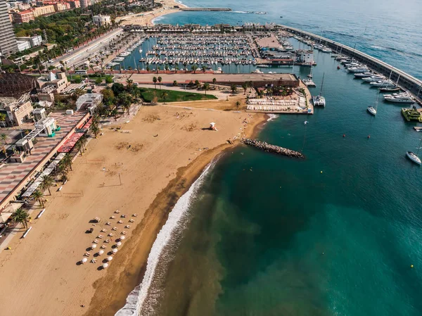 Drone shot Barcelona. Port with boats near the coast. Drone view of a vibrant swimming and sunbathing beach in Barcelona. People are relaxing on the beach. Panoramic view of the city of Barcelona.