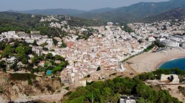 Tossa de Mar 'daki deniz manzaralı kalenin drone görüntüsü. İspanya 'da bir belediyenin insansız hava aracı çekimi. İnsanlar İspanya 'da kumlu bir plajda dinleniyor. Akdeniz yakınlarındaki bir kaplıca kasabası