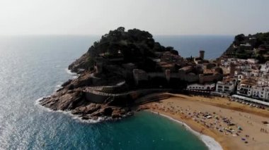 Tossa de Mar 'daki deniz manzaralı kalenin drone görüntüsü. İspanya 'da bir belediyenin insansız hava aracı çekimi. İnsanlar İspanya 'da kumlu bir plajda dinleniyor. Akdeniz yakınlarındaki bir kaplıca kasabası
