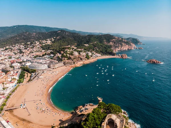 Tossa de Mar 'daki deniz manzaralı kalenin drone görüntüsü. İspanya 'da bir belediyenin insansız hava aracı çekimi. İnsanlar İspanya 'da kumlu bir plajda dinleniyor. Akdeniz yakınlarındaki bir kaplıca kasabası