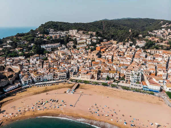 Tossa de Mar 'daki deniz manzaralı kalenin drone görüntüsü. İspanya 'da bir belediyenin insansız hava aracı çekimi. İnsanlar İspanya 'da kumlu bir plajda dinleniyor. Akdeniz yakınlarındaki bir kaplıca kasabası