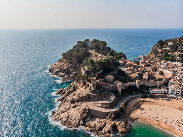 Tossa de Mar 'daki deniz manzaralı kalenin drone görüntüsü. İspanya 'da bir belediyenin insansız hava aracı çekimi. İnsanlar İspanya 'da kumlu bir plajda dinleniyor. Akdeniz yakınlarındaki bir kaplıca kasabası