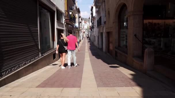 一对年轻夫妇正沿着托萨 玛尔的老街散步 在西班牙 一个男人和一个女孩走过一条狭窄的街道 西班牙东部的度假胜地 — 图库视频影像