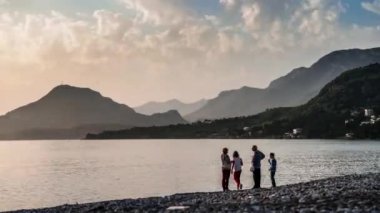Karadağ Bar 'da gün batımı ve dağ manzarası. Baraj seti. İnsanlar deniz kenarında plajda dinleniyorlar. Karadağ 'daki yeşil dağlar ve deniz manzarası. Tatil köyü
