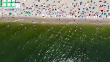 Deniz kenarındaki kumlu bir sahilde dinlenen insansız hava aracının görüntüsü. İnsanlar Odessa 'da Karadeniz' de güneşlenip yüzüyor. Yaz tatili. Denizde tatil. Temiz deniz kıyısında dinlenme. Spa tatili