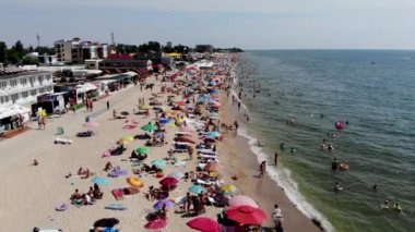 Deniz kenarındaki kumlu bir sahilde dinlenen insansız hava aracının görüntüsü. İnsanlar Odessa 'da Karadeniz' de güneşlenip yüzüyor. Yaz tatili. Denizde tatil. Temiz deniz kıyısında dinlenme. Spa tatili