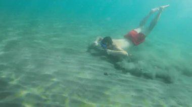 Genç bir adam İspanya 'da özel ekipmanları olmadan Akdeniz' de su altında yüzüyor. Adam suyun altına daldı. Kadavralarda serbest dalış. Nefes al-tut dalışı. Platja Grand ve Esportal plajı. 