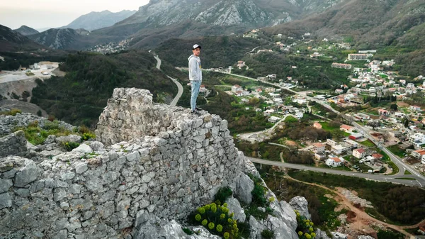 Harap olmuş Hac Nehai kalesinin kıyısında bir vadi ve dağların arkasında duran genç bir adam. Adam Karadağ 'ın dağlarının arka planında poz veriyor. Sutomore 'daki Kale