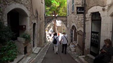 Saint-Paul-de-Vence 'in ortaçağ güçlendirilmiş köyü. Ortaçağ kareleri. Saint-Paul-de-Vence şehrinde insanlar dar bir cadde boyunca yürüyorlar. Güney Fransa