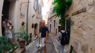 Saint-Paul-de-Vence 'in ortaçağ güçlendirilmiş köyü. İnsanlar Saint-Paul-de-Vence 'de dar bir sokakta yürüyor. Dar bir sokakta hediyelik eşya dükkanları ve galeriler 