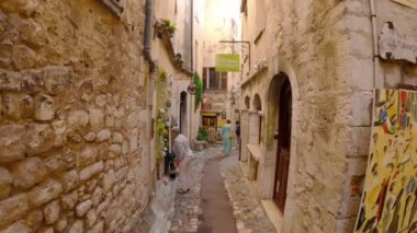 Saint-Paul-de-Vence 'in ortaçağ güçlendirilmiş köyü. İnsanlar Saint-Paul-de-Vence 'de dar bir sokakta yürüyor. Dar bir sokakta hediyelik eşya dükkanları ve galeriler 