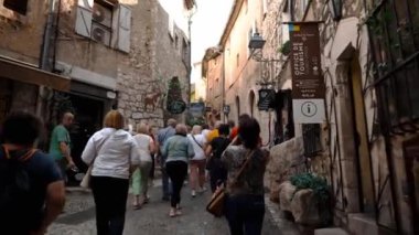 Saint-Paul-de-Vence 'in ortaçağ güçlendirilmiş köyü. İnsanlar Saint-Paul-de-Vence 'de dar bir sokakta yürüyor. Dar bir sokakta hediyelik eşya dükkanları ve galeriler 