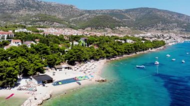 İnsansız hava aracı Hırvatistan 'ın Brac adasındaki bir rüzgar sörfü okuluna ateş açtı. İnsanlar plajda dinleniyor. Güneş pansiyonlarında güneşlenen turistlerin insansız hava aracı görüntüsü. İHA 'dan Bol view tatil beldesi