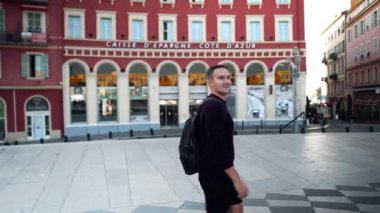 Mutlu genç bir adam Nice meydanında yürüyor. Fransa 'nın eski Nice şehrinin en büyük ve en güzel meydanı. Massena Nice 'de. Sahip Meydanı.
