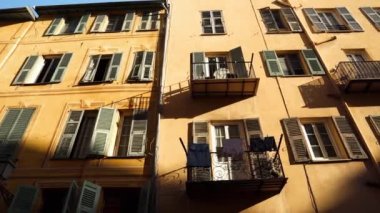 A colorful residential building in Nice. Antique window shutters in France. City streets in the French city of Nice. Beautiful streets of Nice. Center of Nice. Laundry drying on small balconies
