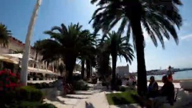 Croatian city of Split in the resort region of Dalmatia. Embankment Riva. Lively promenade with palm trees near the Adriatic Sea. Time lapse embankment near the sea in Croatia