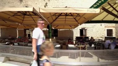 People sit in a cafe on the waterfront in Trogir. Old town of Trogir. People at the resort. Holidays at sea in Croatia. City of Trogir on the coast of Central Dalmatia