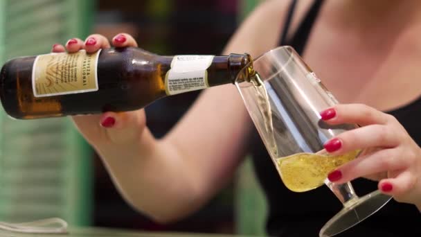 Ragazza versa birra da una bottiglia in un bicchiere — Video Stock