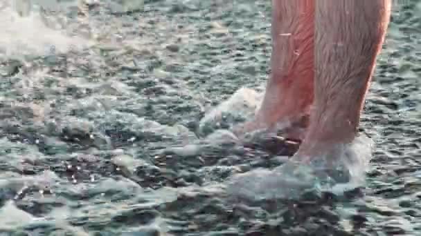 Biała piankowa fala uderza w nogi na plaży. — Wideo stockowe