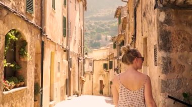 Elbiseli bir kadın turistik şehirde yürüyor.