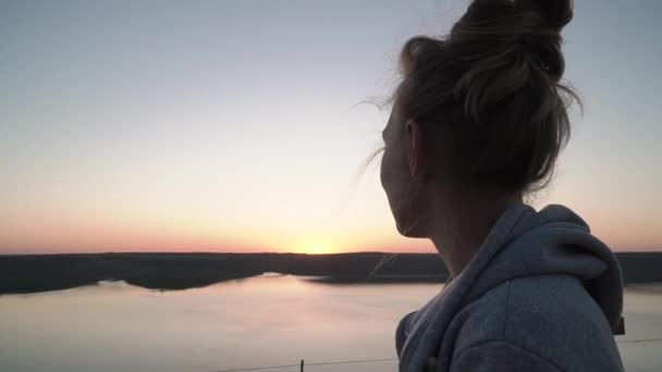 Vrouw bewondert zonsondergang boven het meer — Stockvideo