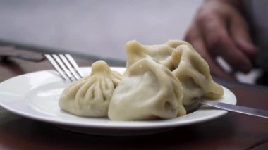 Tabakta taze pişmiş Gürcü hamur tatlısı. Yaşlı adam elleriyle yemek seçiyor ve hepsini yiyor.. 