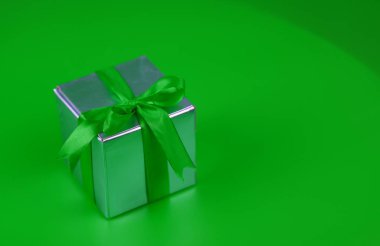 Yeşil ambalajlı hediye. Yeşil arka plandaki bir adam için hediye. 8 Mart için yeşil kurdeleli bir hediye..