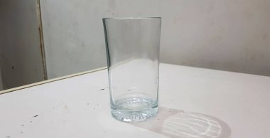 Beyaz arka planda izole edilmiş gölgesi olan parlak bir su bardağının yakın görüntüsü.