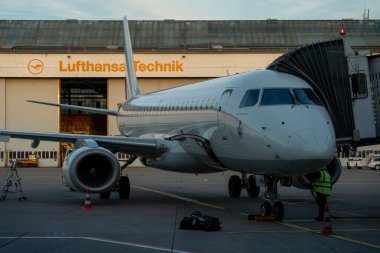 İşçiler Lufthansa atölyesinin önündeki Lufthansa uçağını inceliyor.