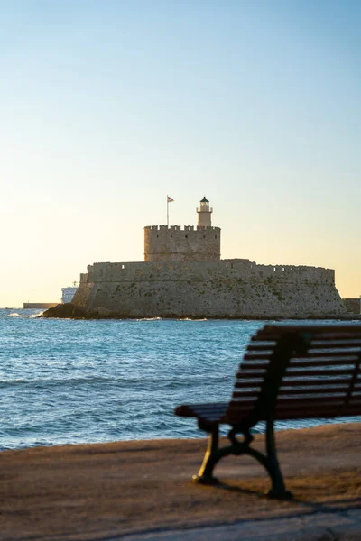 Mandraki Limanı 'ndaki Aziz Nicholas Kalesi ve gün batımında deniz kenarı koltuğu .