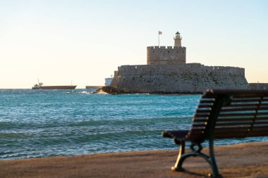 Mandraki Limanı 'ndaki Aziz Nicholas Kalesi ve gün batımında deniz kenarı koltuğu .