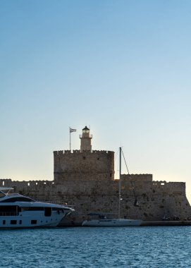 Mandraki Limanı 'ndaki Aziz Nicholas Kalesi odak noktası ve gündüz vakti deniz kenarı koltuğu.