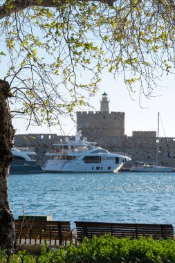 Mandraki Limanı 'ndaki Aziz Nicholas Kalesi odak noktası ve gündüz vakti deniz kenarı koltuğu.