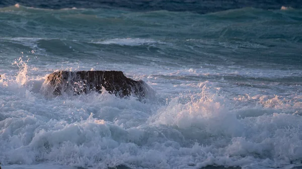 ビーチで岩を打つ夕日の海の波 — ストック写真