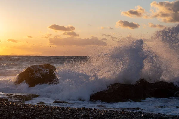 ビーチで岩を打つ夕日の海の波 — ストック写真