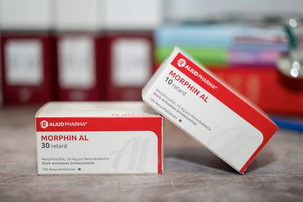 İlaç kutusu morfin, ağrı kesici. Masada ve arka planda farklı tıp kitapları var..