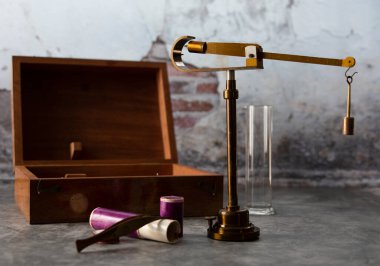 Eski tip eczacılık terazisi, arka plan olarak eski duvarın ağırlığını ölçüyor..