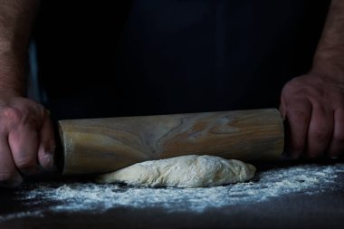 Man Baker ya da şef ahşap bir yüzey üzerinde hamur rulosu ile taze hamur rulo.