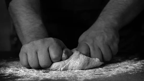 パン屋で新鮮なパンを焼く 小麦粉とキッチンテーブルの上に男性の膝生地の手 — ストック写真