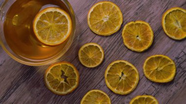 Tahta zemin üzerinde limon dilimleri ve kuru portakal dilimleri olan fincan çayı.