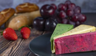 Dutch cheese types on plate and bread and fruit on wooden backdrop