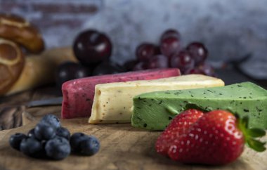 Dutch cheese types on plate and bread and fruit on wooden backdrop
