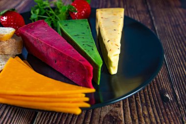 Dutch cheese types on plate and bread and fruit on wooden backdrop