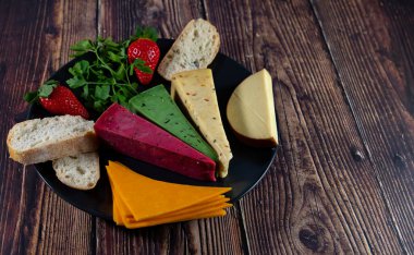 Dutch cheese types on plate and bread and fruit on wooden backdrop