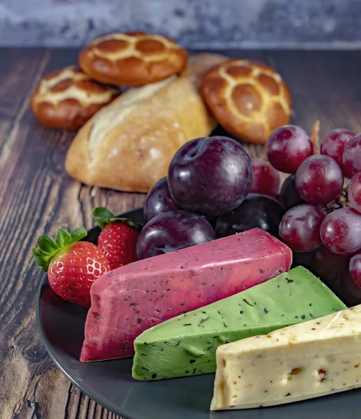 Dutch cheese types on plate and bread and fruit on wooden backdrop